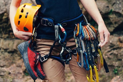 Woman standing with climbing equipment and helmet outdoor, front view. Face is not visible