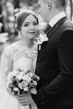 the bride and groom are walking in a pine forest on a bright day