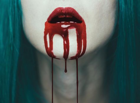 Blood is flowing from the mouth of a woman. Close-up image of red lips. Halloween or horror theme
