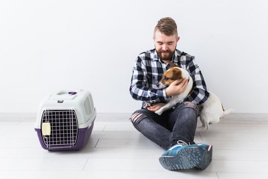 Dog carrying bags and pets owner concept - Attractive cheerful male in plaid shirt holds favourite pet. Happy bearded man with his jack russell terrier.