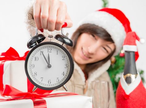 Woman in santa hat shows the clock in Christmas atmosphere