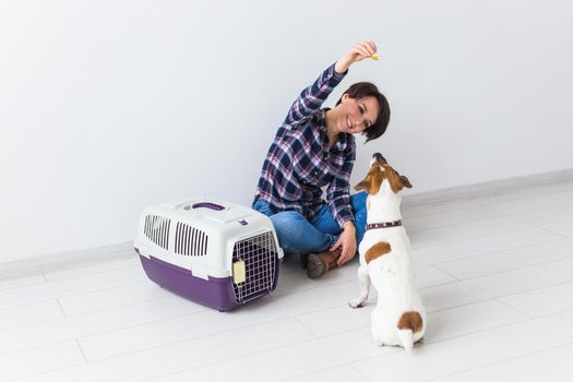 Dog carrying bags and pets owner concept - Attractive cheerful female in plaid shirt holds favourite pet. Happy woman with her jack russell terrier.