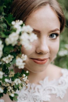 bride with a wedding bouquet in the forest near the bushes blooming with white flowers