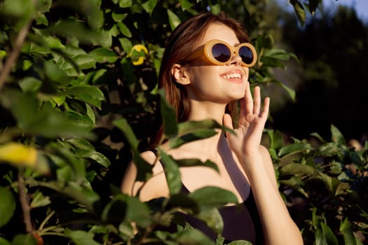 cheerful woman wearing sunglasses green leaves nature summer posing. High quality photo