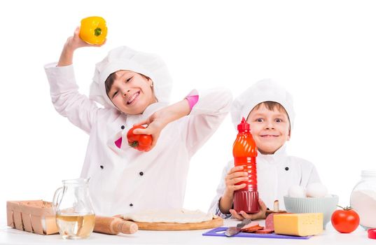 cute little boy and girl in white uniform with ingredients for pizza
