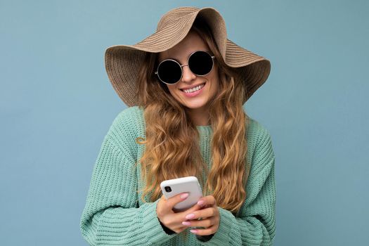 Beautiful young woman wearing casual clothes standing isolated over background surfing on the internet via phone looking at mobile screen.