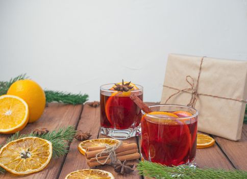 Christmas mulled red wine with spices and fruits on a wooden rustic table. Traditional hot drink at Christmas time.