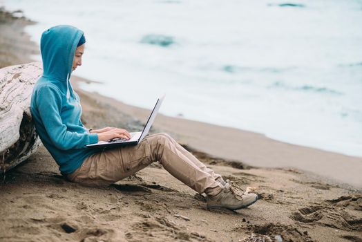 Freelancer young woman working on laptop on beach near the sea. Freelance concept