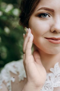 bride with a wedding bouquet in the forest near the bushes blooming with white flowers