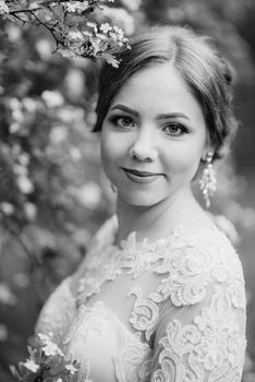 bride with a wedding bouquet in the forest near the bushes blooming with white flowers