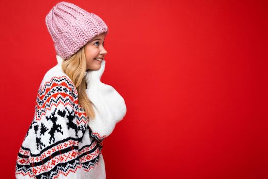 Side-profile photo of pretty smiling happy young blonde woman standing isolated over colourful background wall wearing everyday trendy clothes looking to the side. Empty space, copy space
