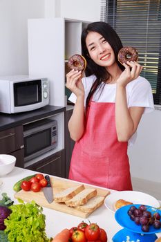 young woman with a chocolate donut in hand, kitchen room