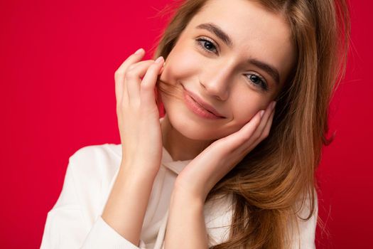 Young smiling sexy beautiful dark blonde woman with sincere emotions isolated on background wall with copy space wearing casual white hoodie. Positive concept.