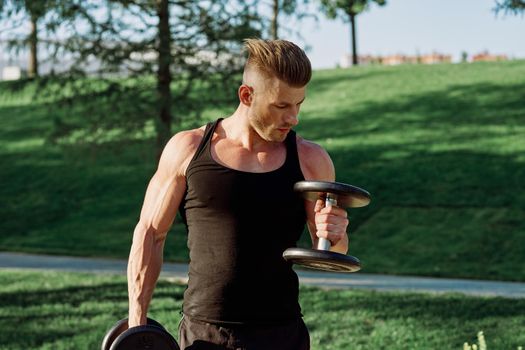 pumped up sports Vykhino in the park with dumbbell workout. High quality photo