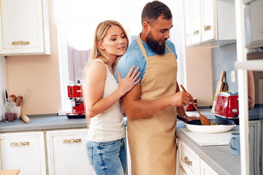 Young loving couple cooking together in kitchen at home