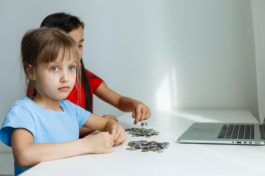 portrait of little girls sitting at table and calculating money