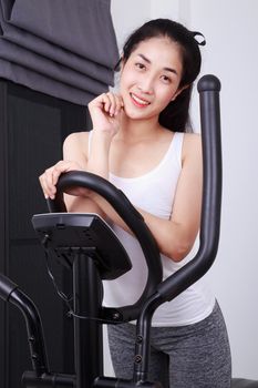 young sporty woman doing exercises with elliptical trainer