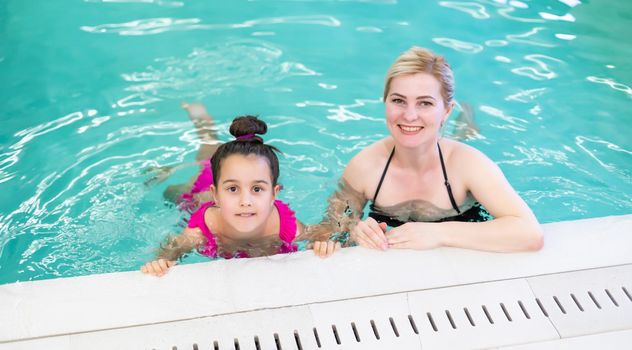 mother and daughter Relaxing By Swimming Pool