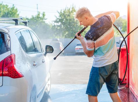 Man is washing car with high pressure water