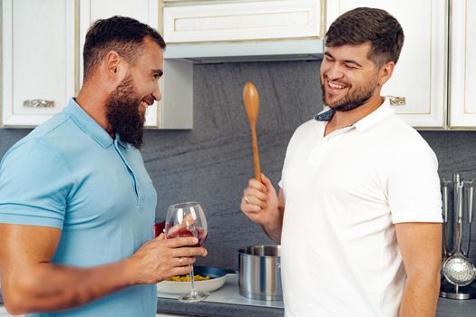 Happy homosexual couple preparing food together in kitchen at their house