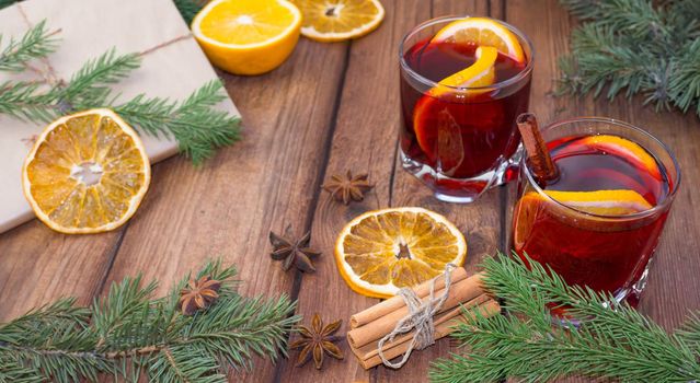 Mulled wine and spices on a wooden background with branches of a Christmas tree. Selective focus.