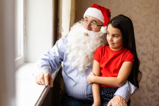 Picture of an elderly man wearing a Santa hat while playing with his grandchildren