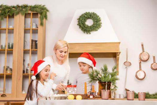 Two girls dressed in red hats are preparing cookies, gingerbread for the New Year holiday, Christmas. Cut out cookies.