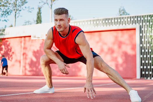 sports man in a red t-shirt on the sports ground doing exercises. High quality photo