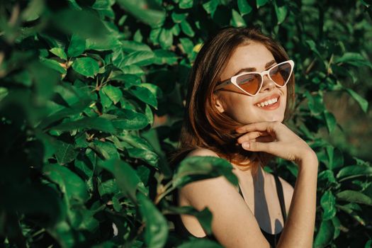 smiling woman wearing sunglasses green leaves nature fashion. High quality photo