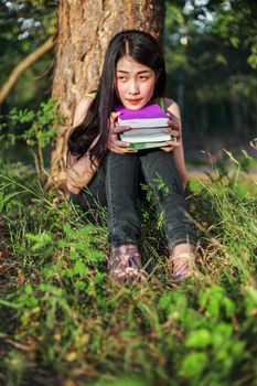 young woman sitting and holding a book in the park