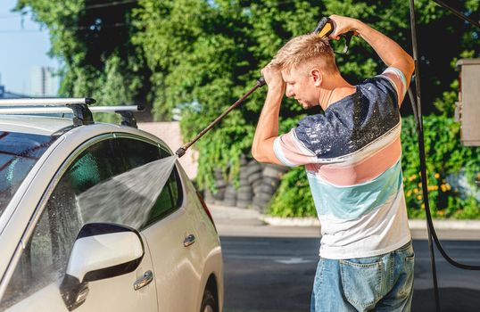 Man is washing car with high pressure water