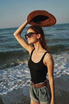 cheerful woman in sunglasses and a hat by the ocean walk summer. High quality photo