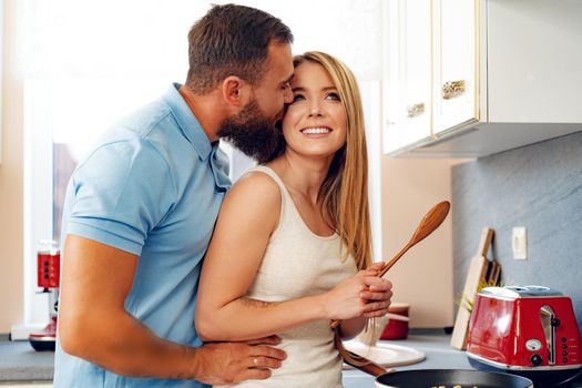 Young loving couple cooking together in kitchen at home