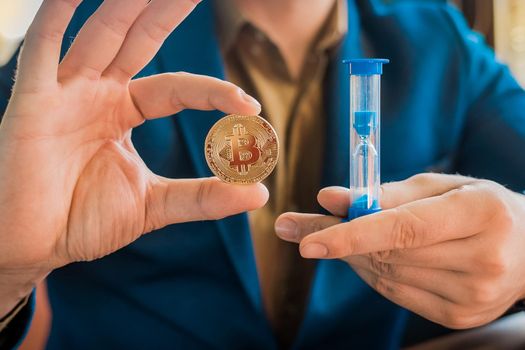 Businessman hands hold gold cryptocurrency bitcoin and hourglass. Cryptocurrency and bitcoin concept.