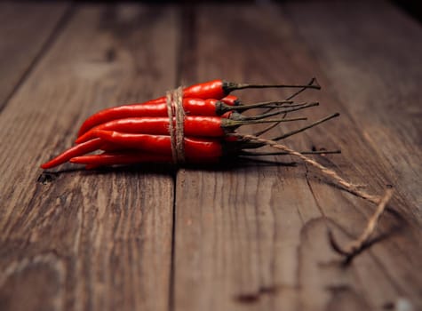 Red chili peppers in a bunch on a wooden table, focus on peppers