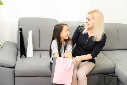 holidays, presents, christmas, x-mas, birthday concept - happy mother and child girl with gift bags