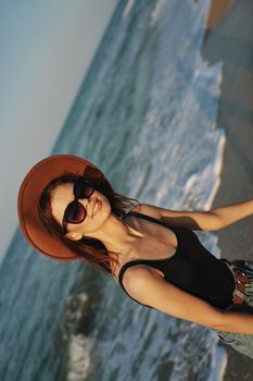 cheerful woman in sunglasses and a hat by the ocean walk summer. High quality photo