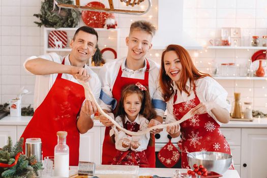 The family is standing in the kitchen and holding the dough in their hands before Christmas.