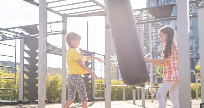 Two cute little girls having fun on a playground outdoors in summer. Sport activities for kids.