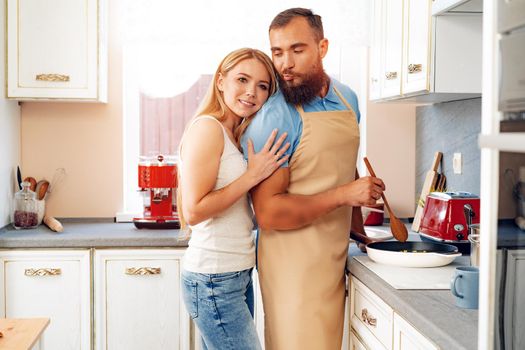 Young loving couple cooking together in kitchen at home