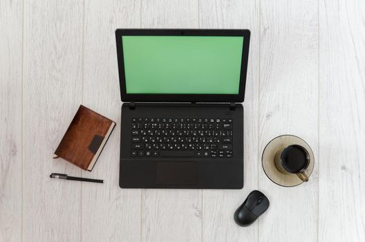 Laptop, mug of coffee and a notebook on the background of a wooden table. Top view