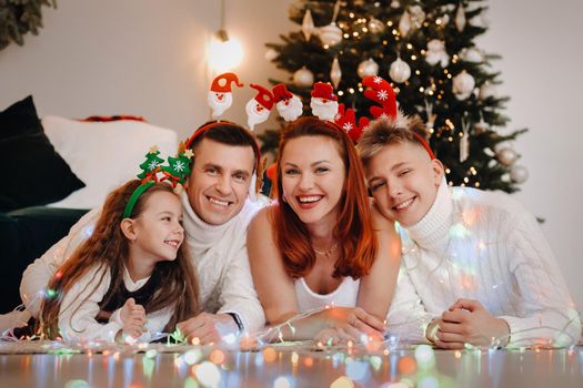 Close-up portrait of a happy family lying near a Christmas tree celebrating a holiday.