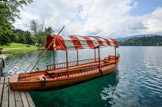 Bled, Slovenia - May 20, 2018: Beautiful Lake Bled in the Julian Alps and old wooden boat. Mountains, clear aquamarine water, tourist boat, lake and dramatic blue sky.