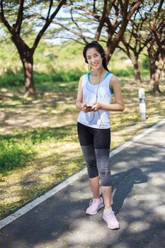 young sporty woman using smartphone with headphone in the park