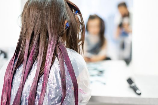 hairdresser dyes hair for a little girl in a hair salon. Dyed, bleached hair