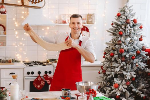 A male chef prepares dough in the Christmas kitchen before the New year.