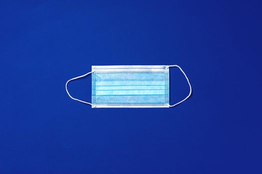 Medical face mask on blue background. Coronavirus covid-19 prevention concept