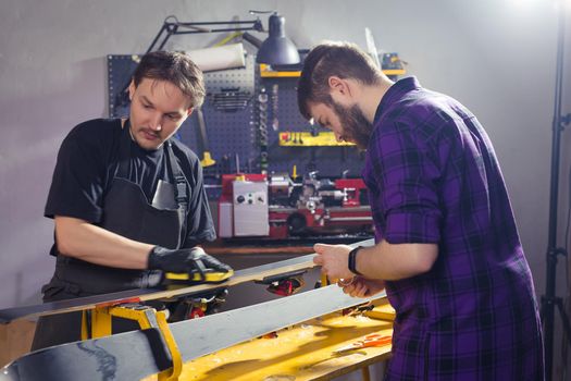 Repair, service concept - a man repairing the ski by rubbing a paraffin