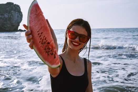 pretty woman in a black swimsuit with a watermelon in her hands summer Ocean. High quality photo