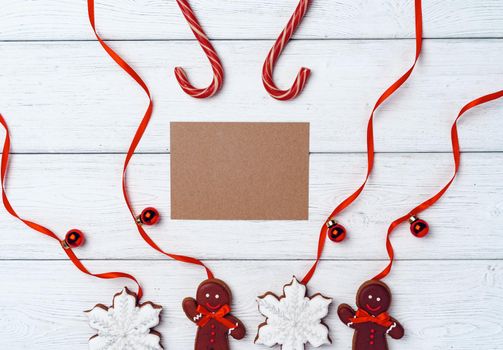 Winter festive background with gingerbread man and candy canes on white wooden board,l copy space